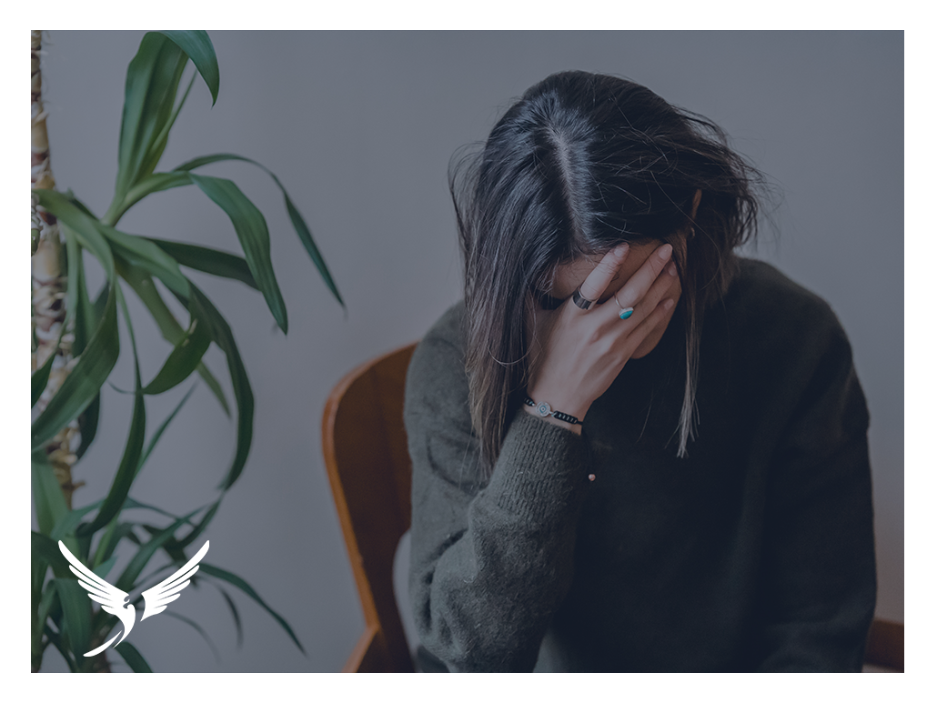 A stressed woman leaning her face into her hand