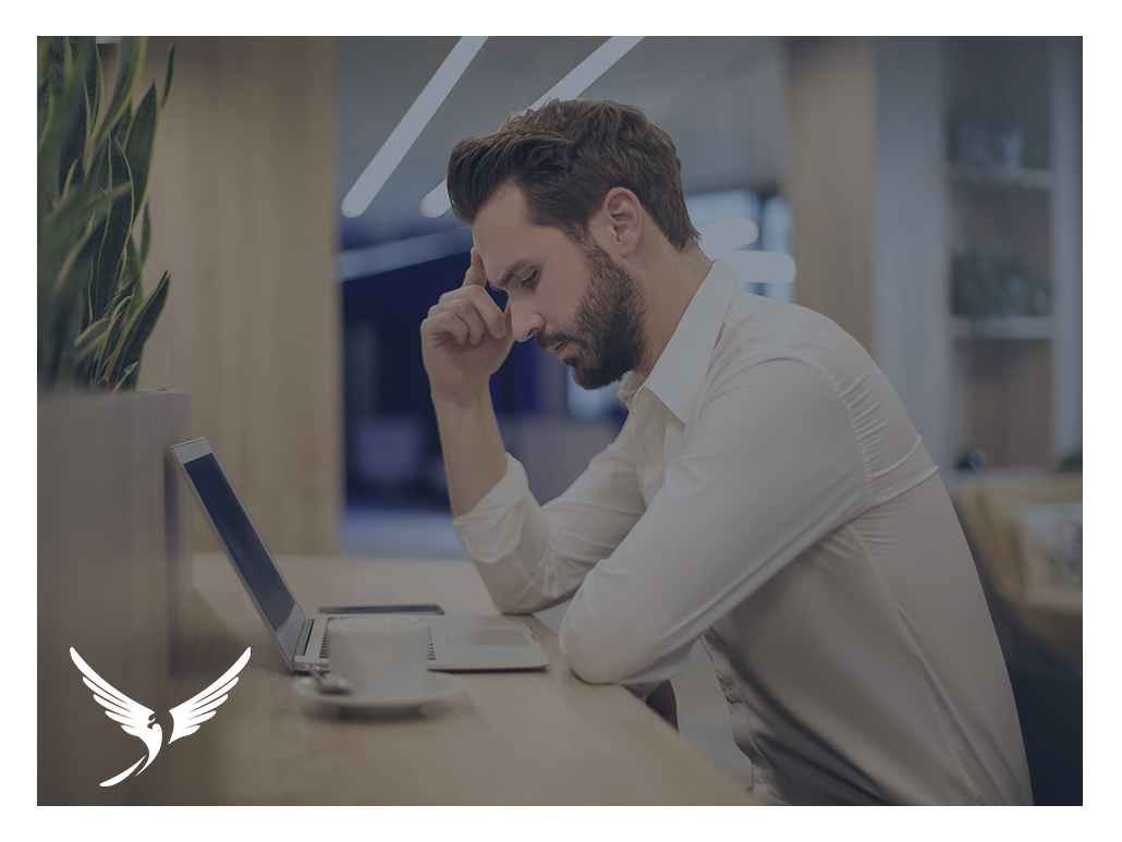 A man experiencing stress working on a laptop